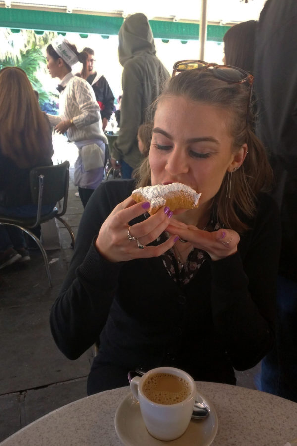 Chloe enjoys the first bite of a beignet with café au lait from Café du Monde.